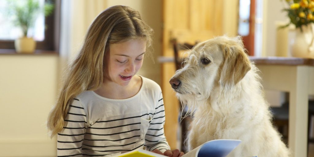 Girl with dog reading book.